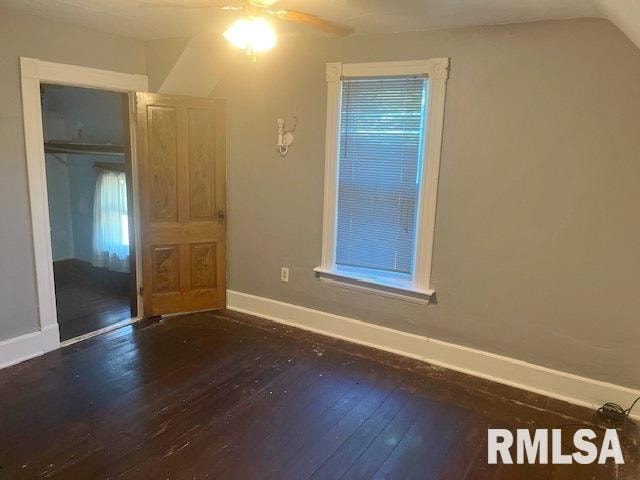 empty room with dark hardwood / wood-style flooring, vaulted ceiling, and ceiling fan