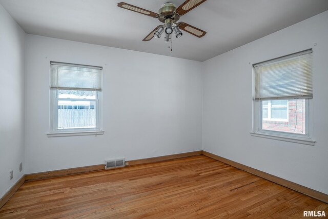 spare room with a wealth of natural light, hardwood / wood-style floors, and ceiling fan