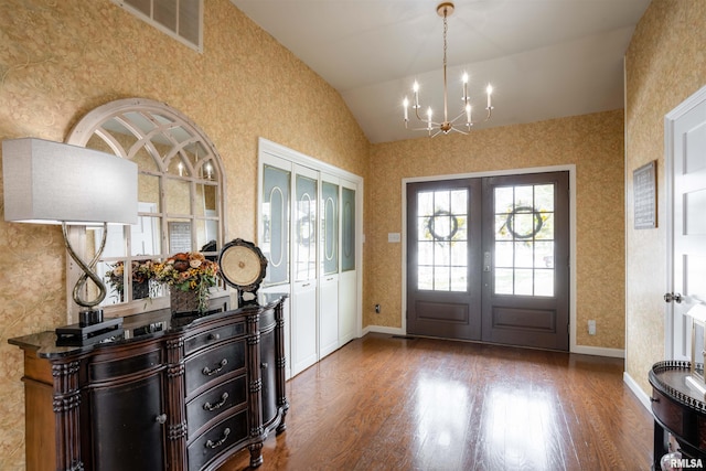 entrance foyer with hardwood / wood-style flooring, french doors, lofted ceiling, and a chandelier