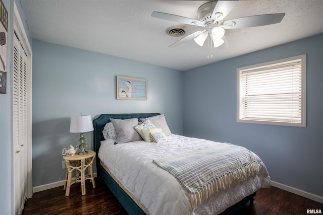 bedroom with ceiling fan, a closet, a textured ceiling, and dark hardwood / wood-style floors