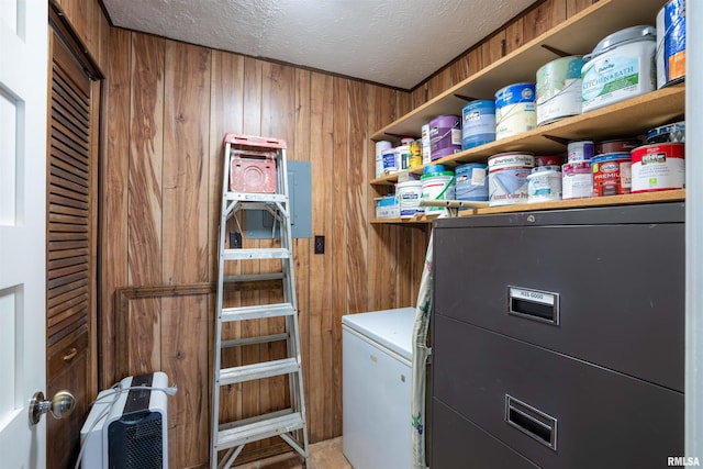 laundry room featuring wood walls and a textured ceiling