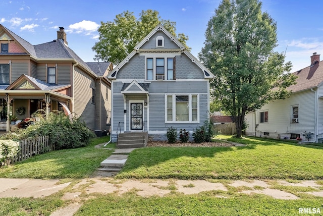 victorian-style house featuring a front lawn and fence