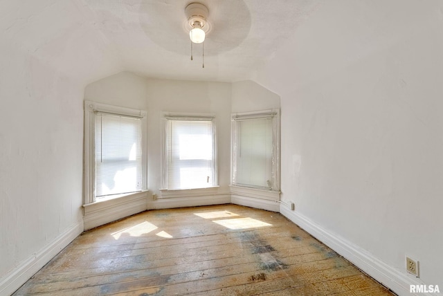 empty room with hardwood / wood-style flooring, baseboards, lofted ceiling, and ceiling fan