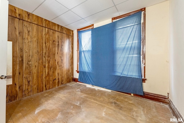 empty room with wooden walls and a paneled ceiling