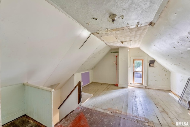 additional living space with hardwood / wood-style flooring and vaulted ceiling