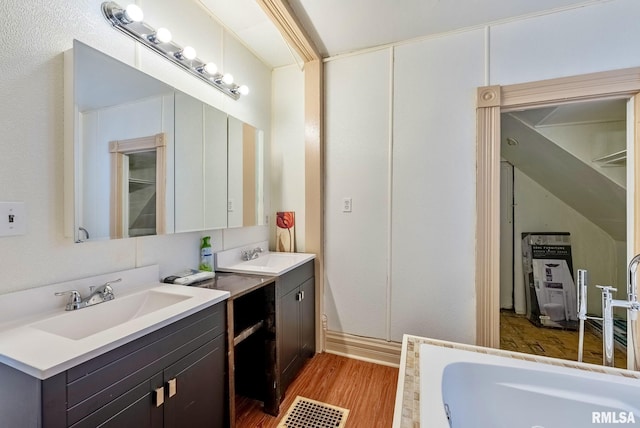 full bathroom with a sink, a jetted tub, two vanities, and wood finished floors