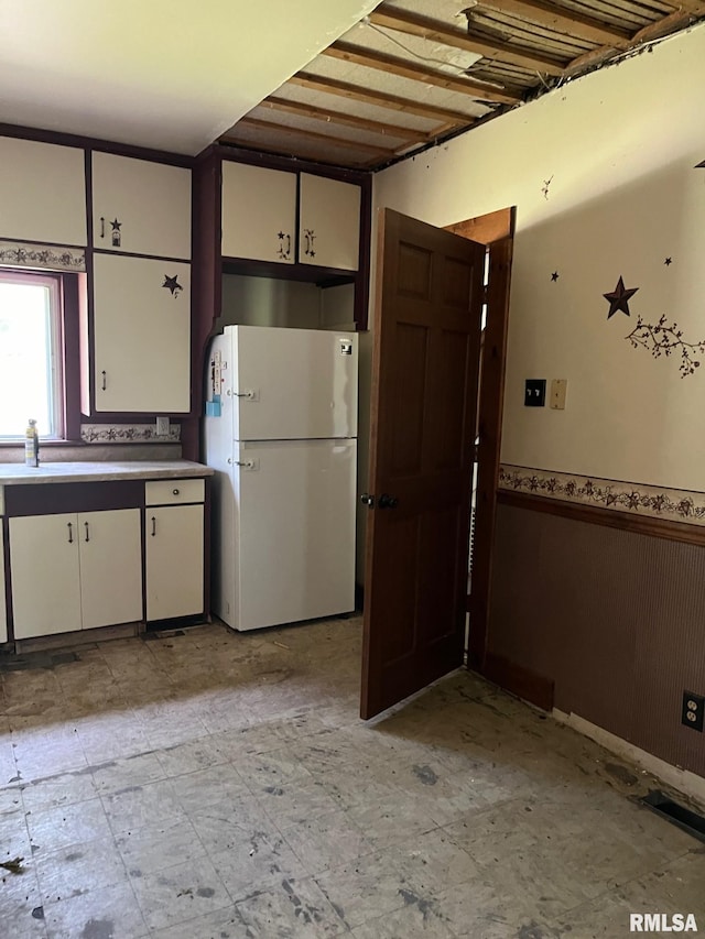 kitchen featuring white refrigerator, light tile patterned floors, and white cabinets