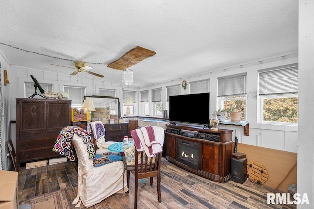 living room with hardwood / wood-style flooring, ceiling fan, and a textured ceiling