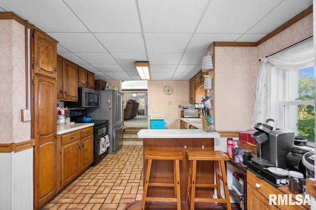 kitchen featuring a breakfast bar area, range with two ovens, and a drop ceiling