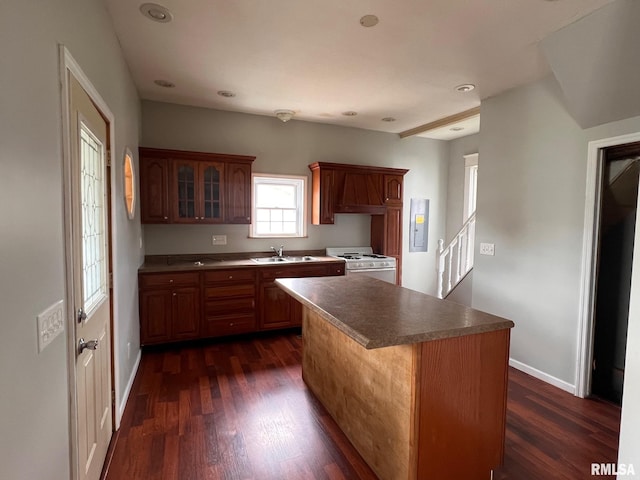 kitchen featuring white stove, dark hardwood / wood-style flooring, a center island, and sink