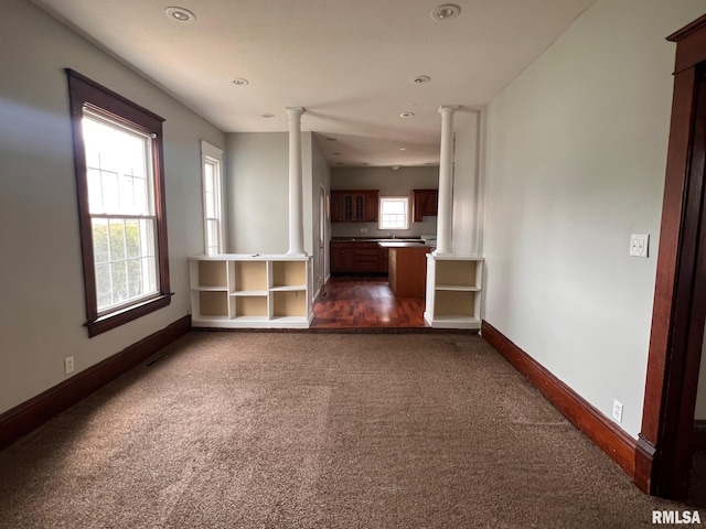 unfurnished living room with dark carpet and decorative columns