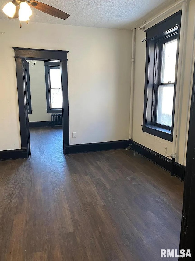 unfurnished room with ceiling fan, radiator, dark hardwood / wood-style flooring, and a textured ceiling