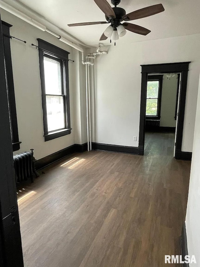 spare room with radiator heating unit, ceiling fan, and dark hardwood / wood-style floors