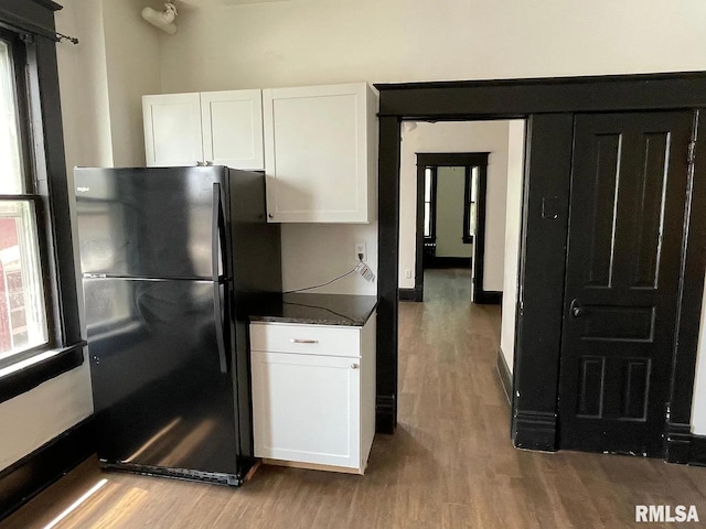 kitchen with white cabinets, black refrigerator, and light hardwood / wood-style floors