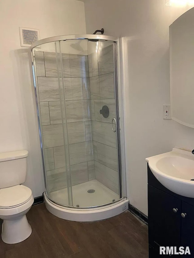 bathroom with vanity, toilet, hardwood / wood-style flooring, and an enclosed shower