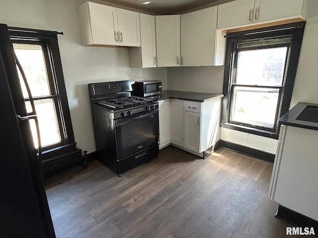 kitchen with black gas range oven, a healthy amount of sunlight, white cabinets, and dark hardwood / wood-style floors