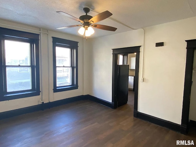 spare room featuring dark wood-type flooring, a textured ceiling, and ceiling fan