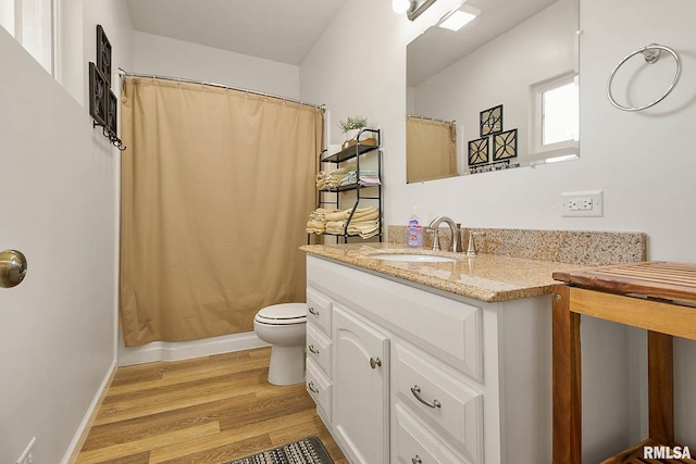 full bath with baseboards, a shower with shower curtain, toilet, wood finished floors, and vanity