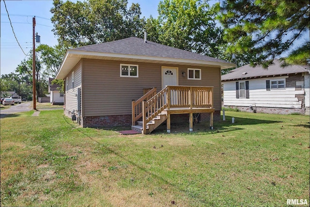 back of property featuring a yard and a shingled roof