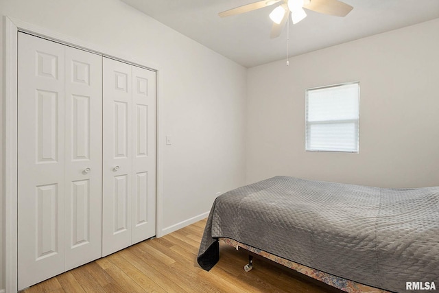 bedroom with ceiling fan, light wood finished floors, a closet, and baseboards