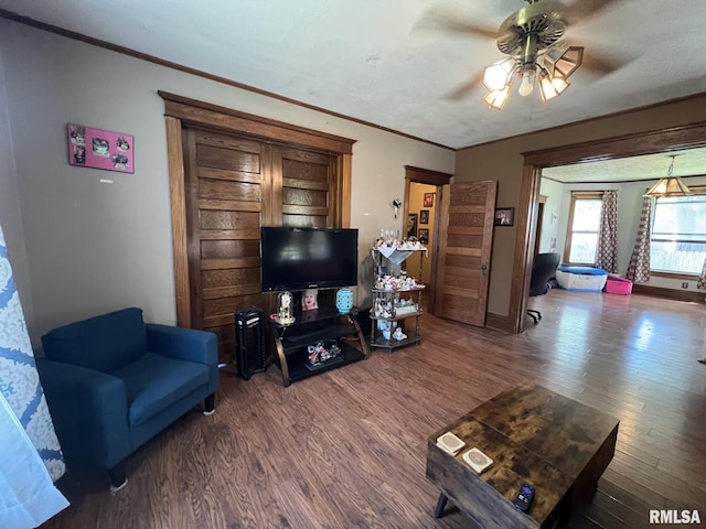 living room with ornamental molding, ceiling fan, dark hardwood / wood-style floors, and a textured ceiling