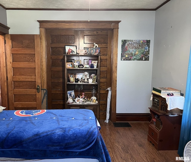 bedroom featuring a textured ceiling, ornamental molding, and dark hardwood / wood-style flooring