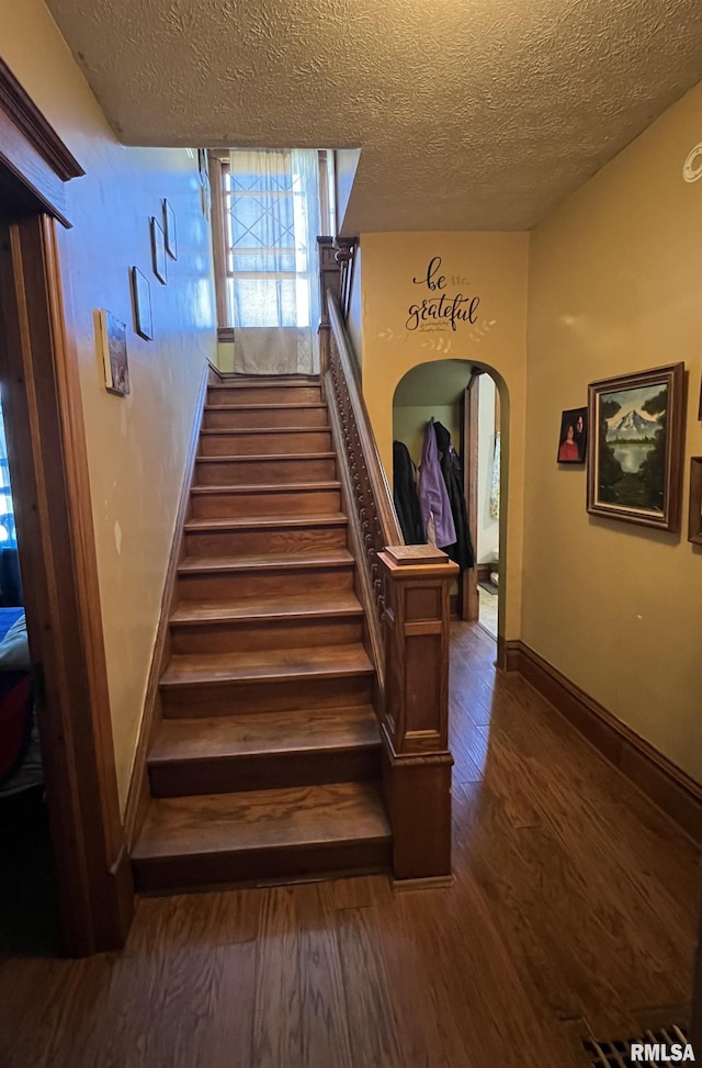 stairs featuring a textured ceiling and hardwood / wood-style flooring