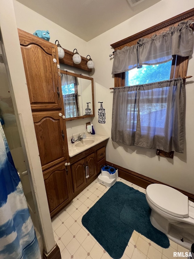 bathroom featuring vanity, toilet, a healthy amount of sunlight, and curtained shower