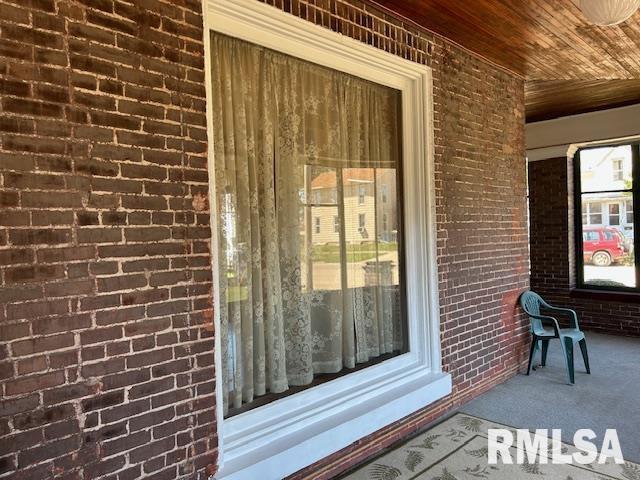 view of exterior entry featuring covered porch and brick siding