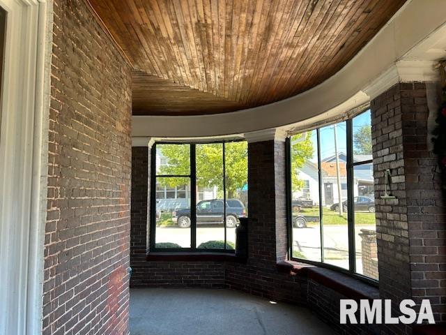 interior space with brick wall, wooden ceiling, and a healthy amount of sunlight