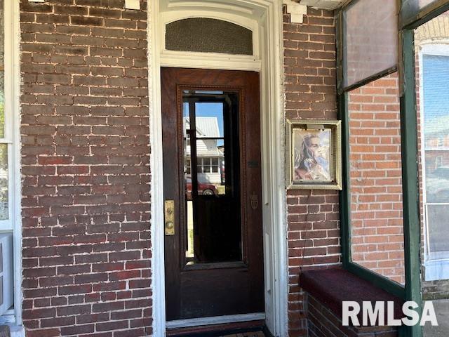 view of exterior entry with brick siding