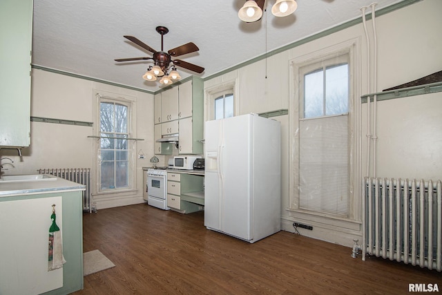 kitchen with dark wood-style floors, radiator, white appliances, and under cabinet range hood