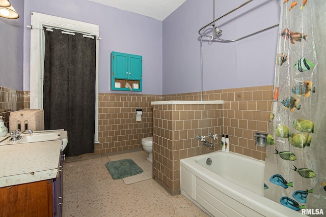 bathroom featuring wainscoting, tile walls, toilet, and vanity