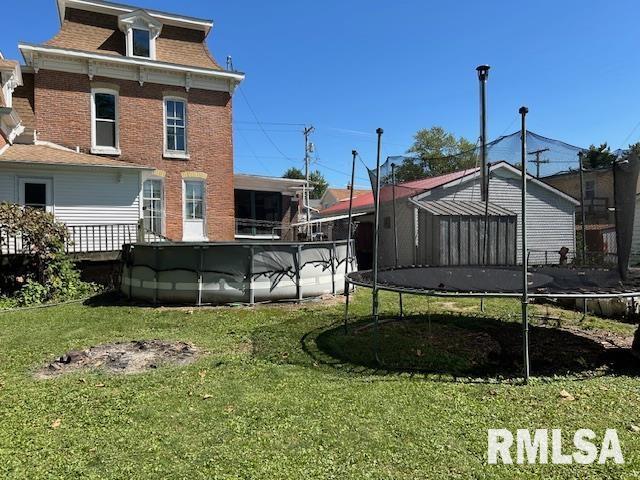 view of yard with a trampoline and a pool