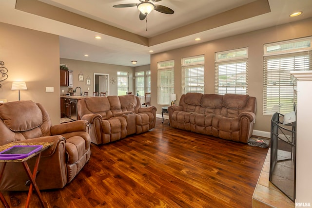 living room featuring sink, ceiling fan, a raised ceiling, and dark wood-type flooring