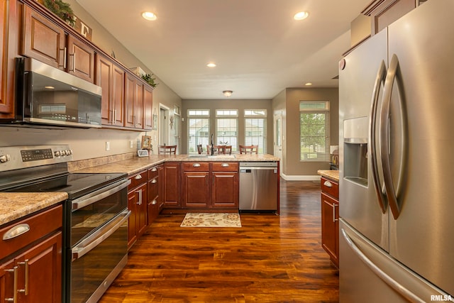 kitchen featuring light stone countertops, sink, stainless steel appliances, dark hardwood / wood-style flooring, and kitchen peninsula