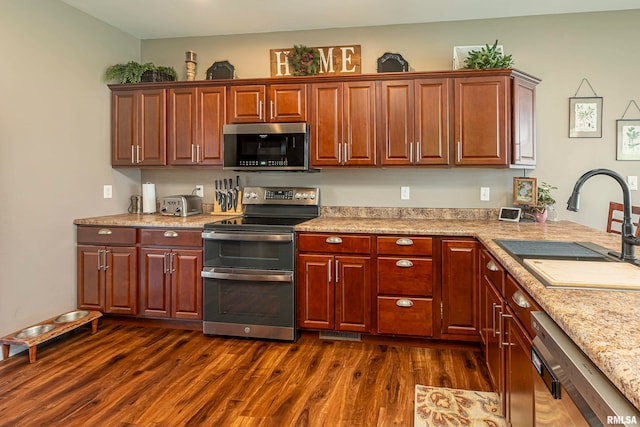 kitchen featuring dark wood-type flooring, light stone countertops, sink, and stainless steel appliances