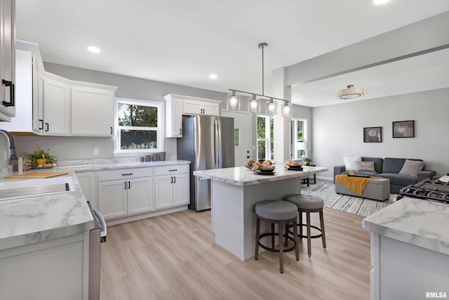 kitchen featuring stainless steel fridge, white cabinetry, a wealth of natural light, and a center island