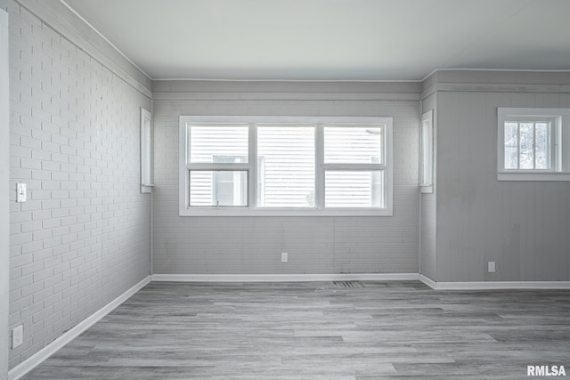 spare room featuring brick wall and hardwood / wood-style flooring