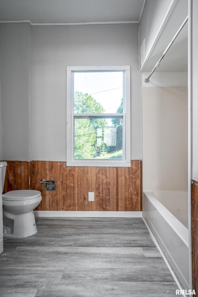 bathroom with wood walls, toilet, and hardwood / wood-style flooring