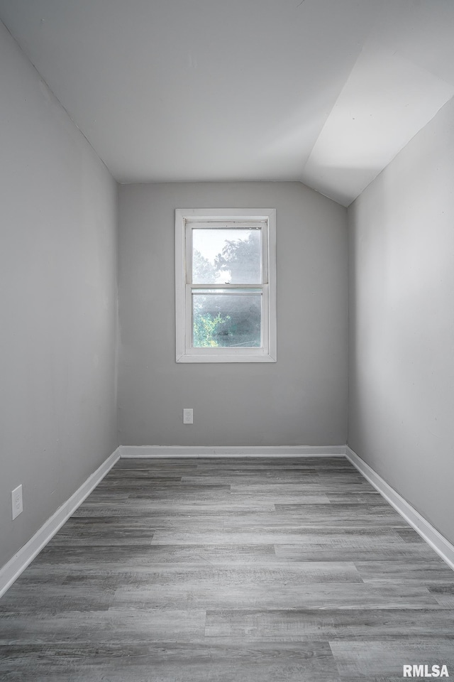 spare room with light wood-type flooring and lofted ceiling