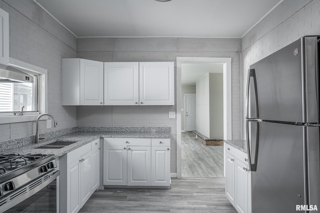 kitchen with light wood-type flooring, appliances with stainless steel finishes, white cabinetry, and sink