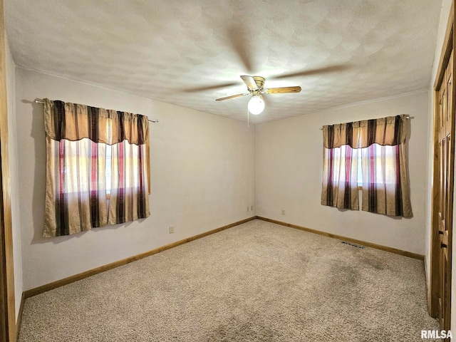 carpeted spare room with a textured ceiling and ceiling fan