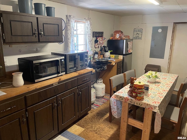 kitchen with appliances with stainless steel finishes, dark brown cabinets, and electric panel