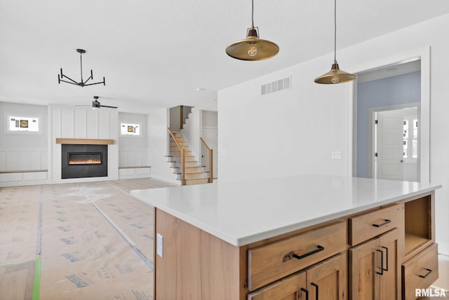 kitchen with ceiling fan, a large fireplace, and hanging light fixtures