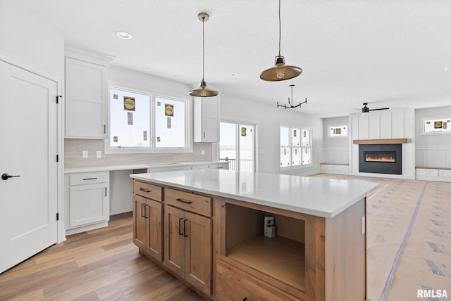 kitchen with decorative light fixtures, light hardwood / wood-style floors, white cabinetry, and a center island