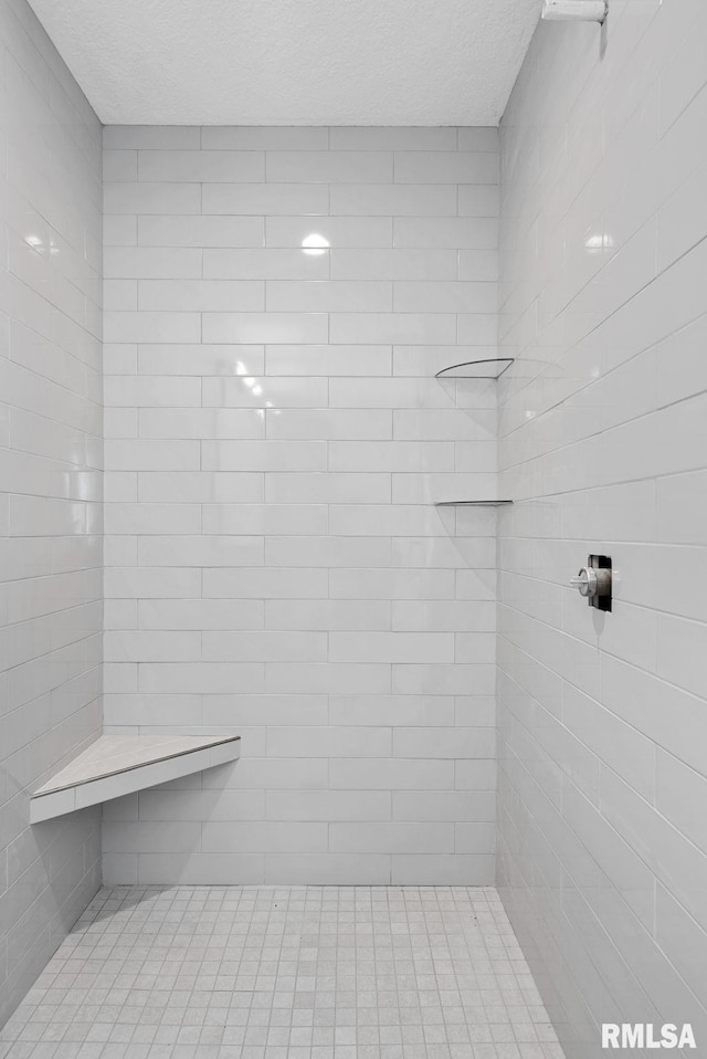 bathroom featuring a textured ceiling and tiled shower