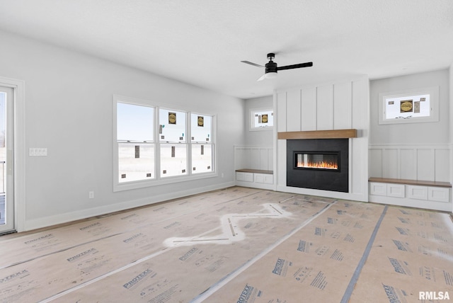 unfurnished living room featuring a wealth of natural light, ceiling fan, and a fireplace