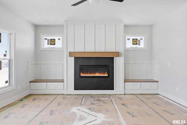 unfurnished living room with a fireplace, ceiling fan, and a healthy amount of sunlight