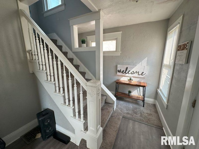 staircase with a textured wall, baseboards, and wood finished floors